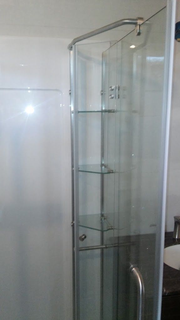 A bathroom with a glass shower door and shelves.