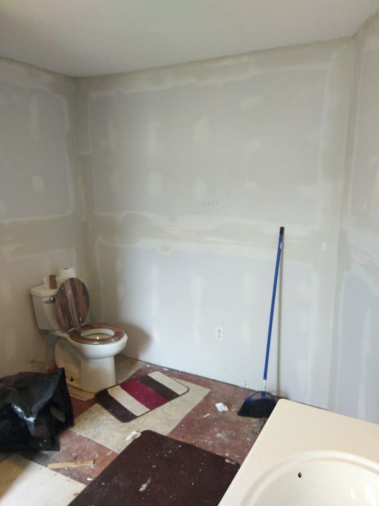 A bathroom with a toilet , sink and broom.