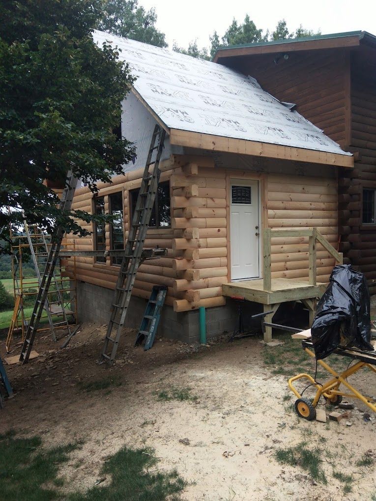 A log cabin is being built with a ladder on the side of it.