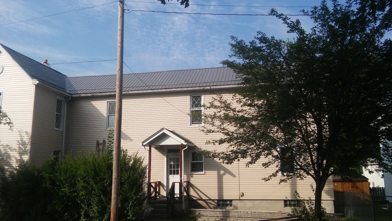A white house with a gray roof and a porch