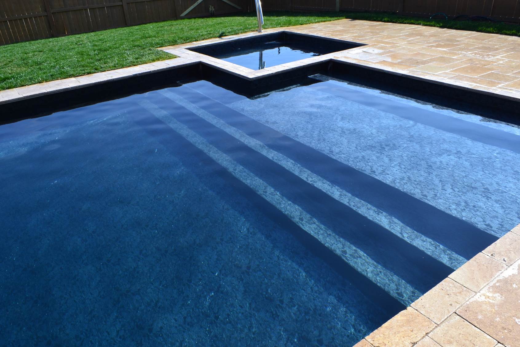 a swimming pool with steps and a fence in the background