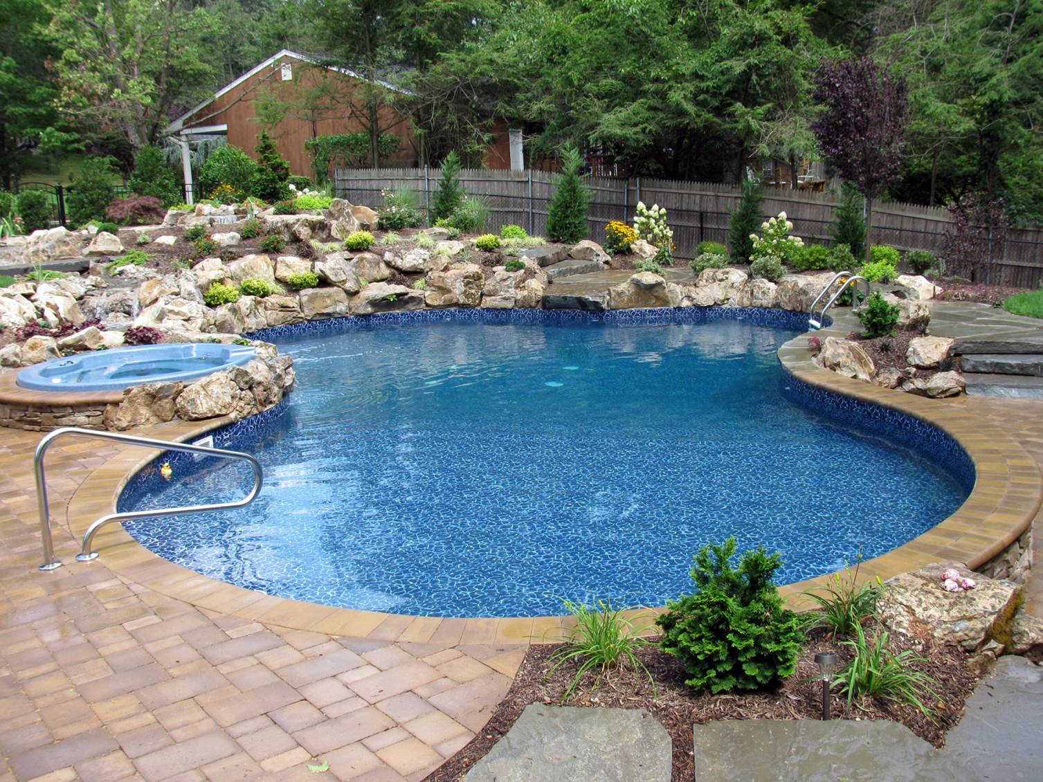 a large swimming pool with a hot tub surrounded by rocks