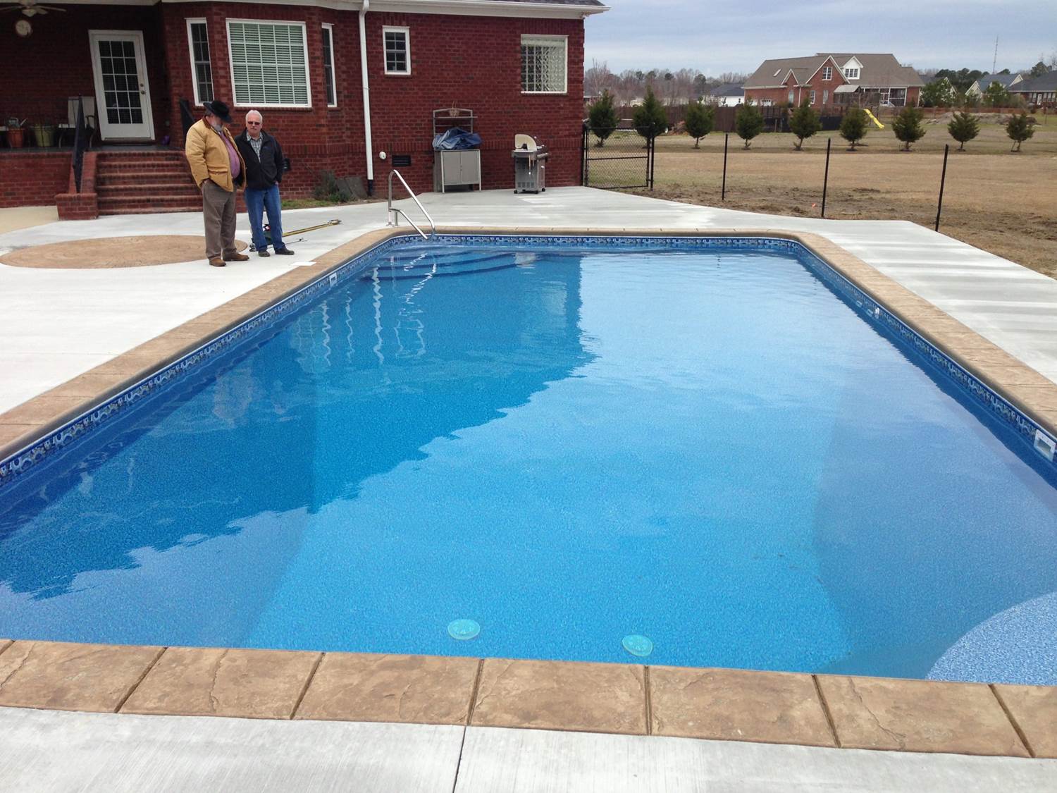 two men stand in front of a large swimming pool