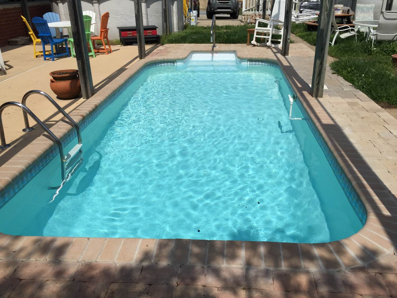 a small swimming pool is surrounded by chairs and a table
