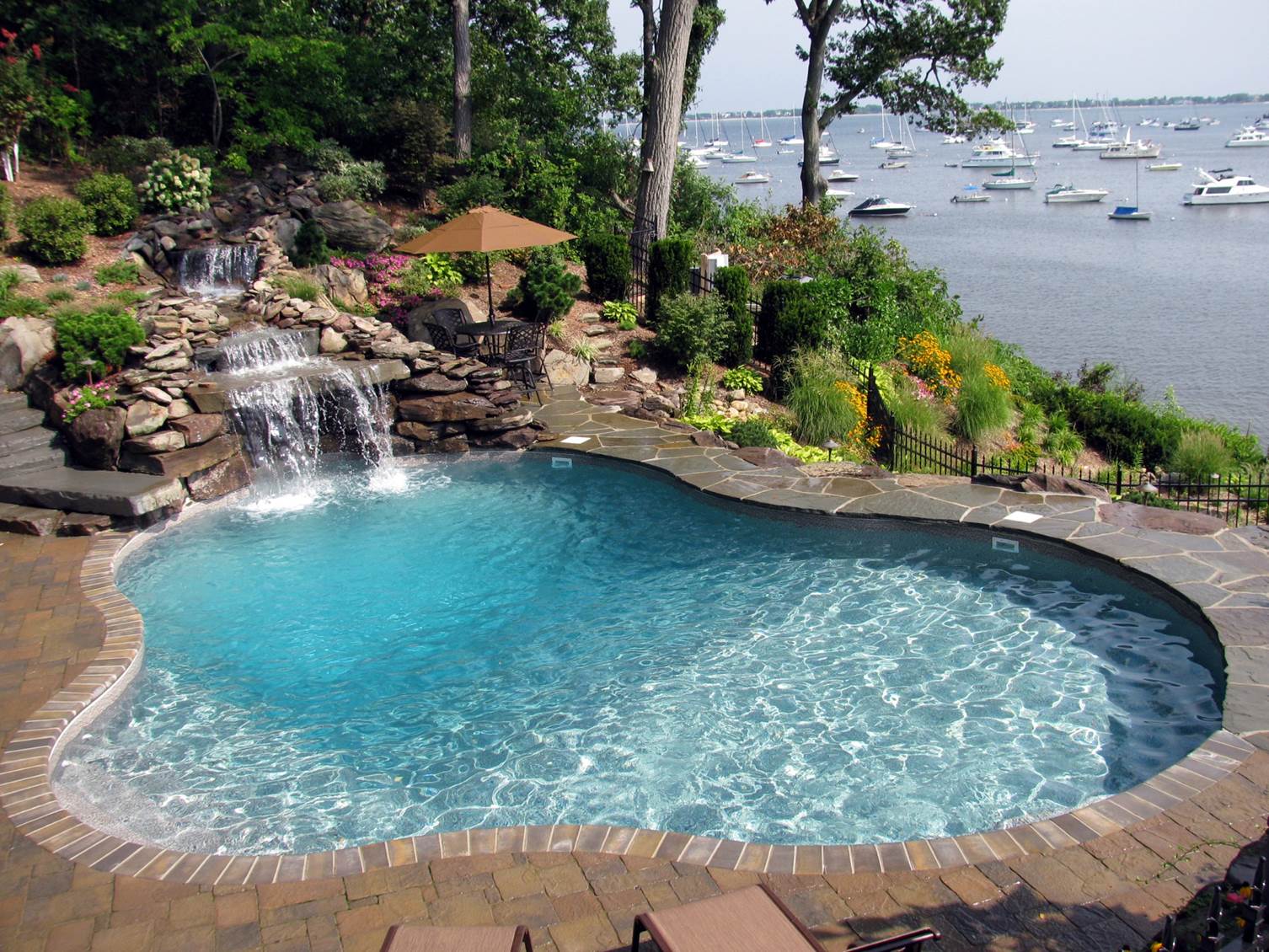 a swimming pool with a waterfall and boats in the background