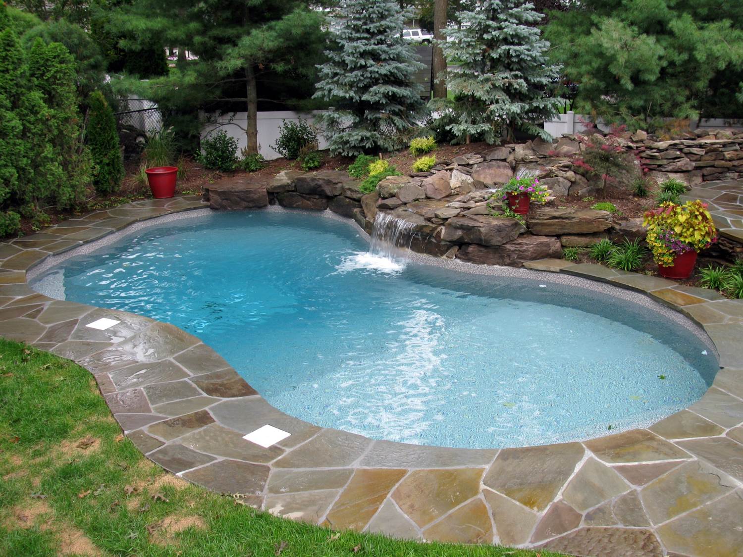 a swimming pool with a waterfall in the backyard