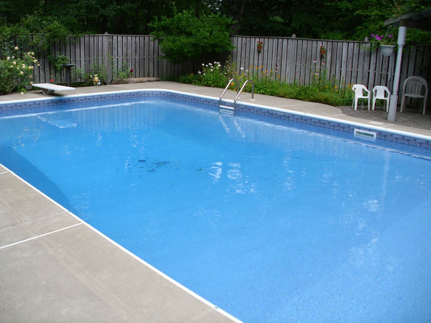 a swimming pool with a wooden fence in the background