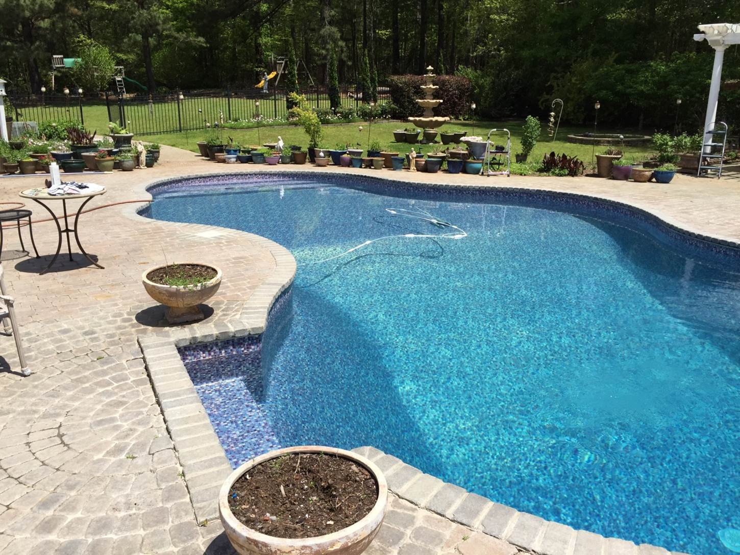 a large swimming pool surrounded by potted plants and a table