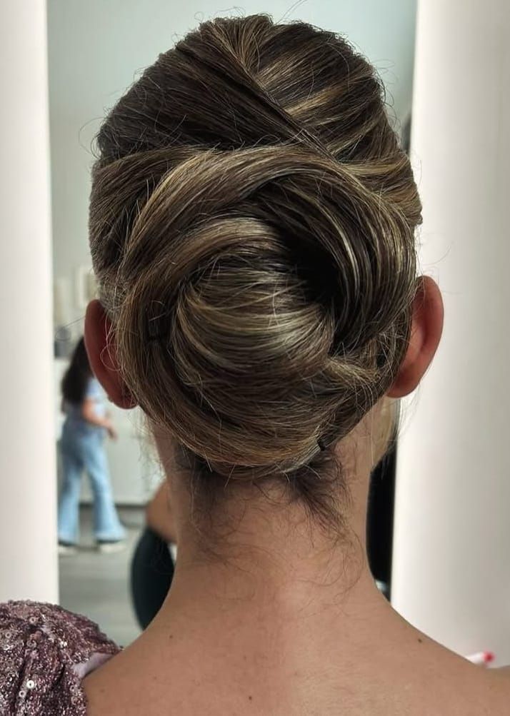 Due persone brindano con dei bicchieri di gin decorati in un bar scarsamente illuminato, festeggiando con altre persone che si intravedono sullo sfondo.