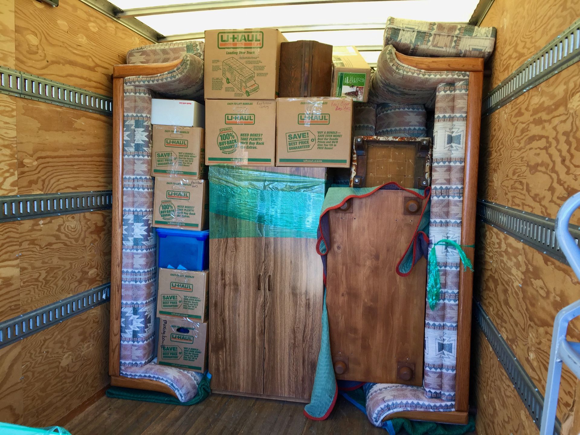 Three people loading a moving truck in a city. Two women and a man are opening the truck and handling the contents.
