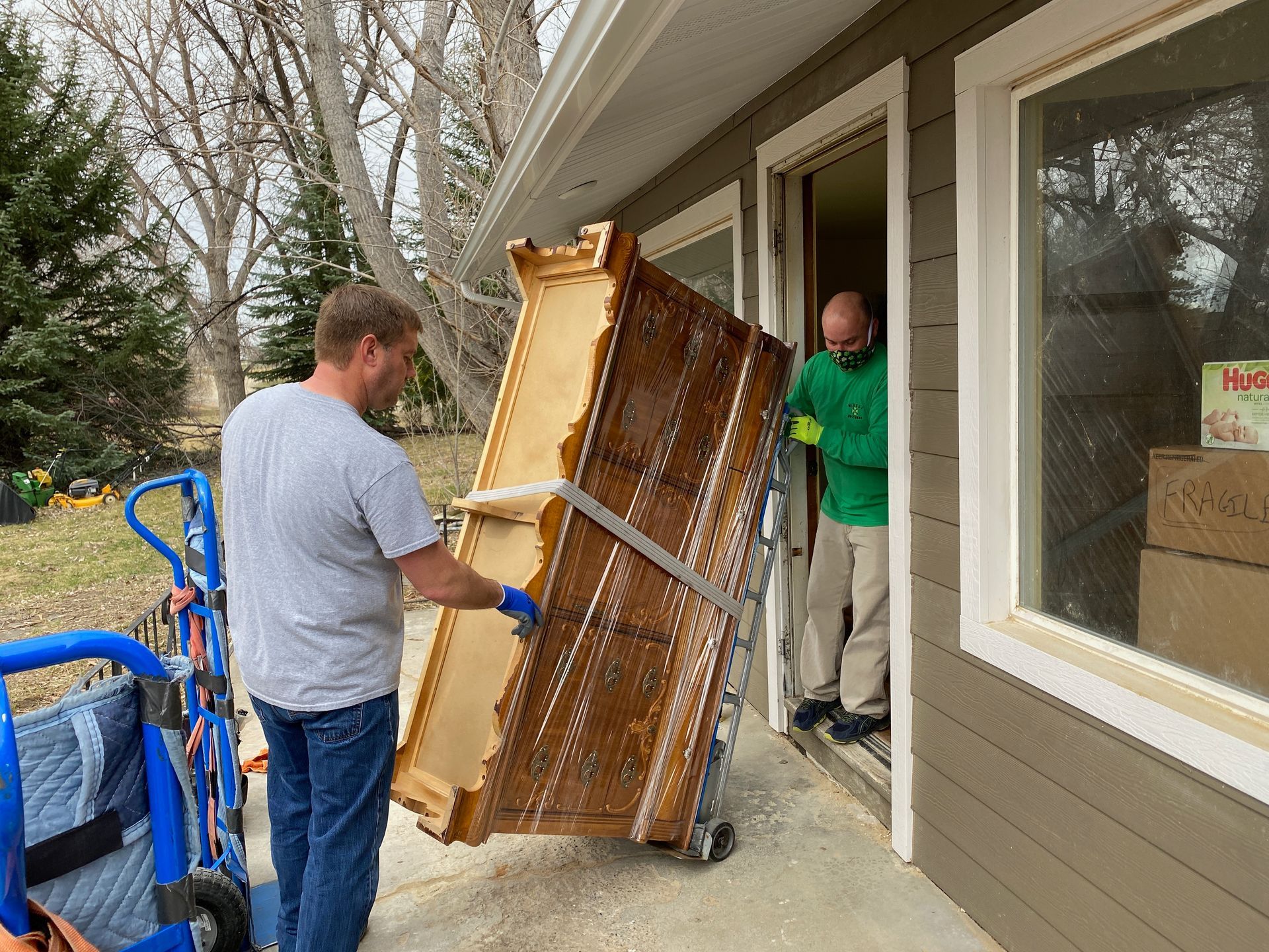 Moving truck parked in front of a house, loading boxes onto the truck. Sunny day, blue sky.