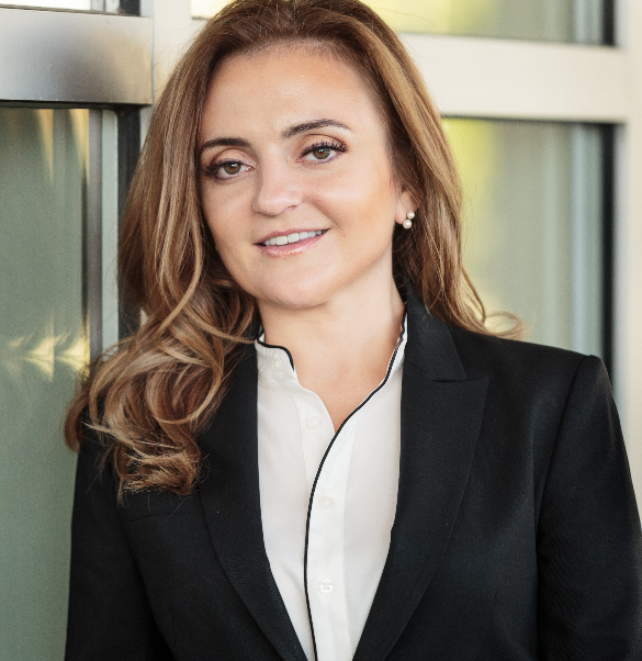 A woman in a black suit and white shirt is smiling