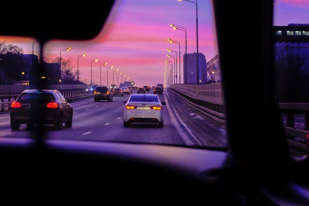 A car is driving down a highway at sunset.