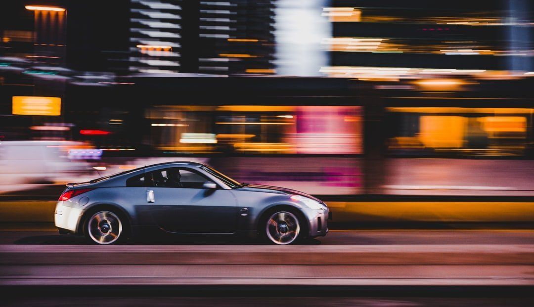 A car is driving down a city street at night.