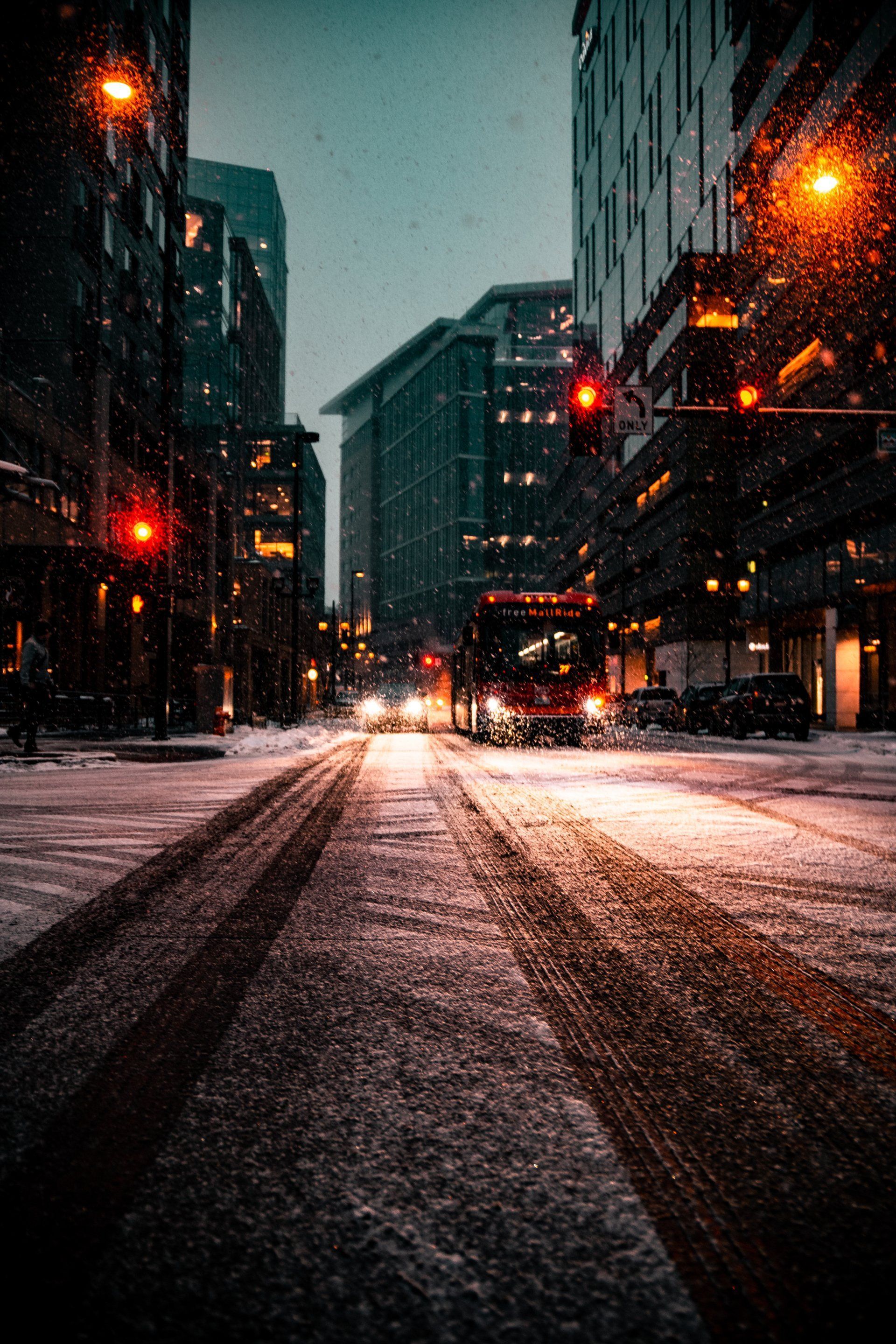 A bus is driving down a snowy city street at night.