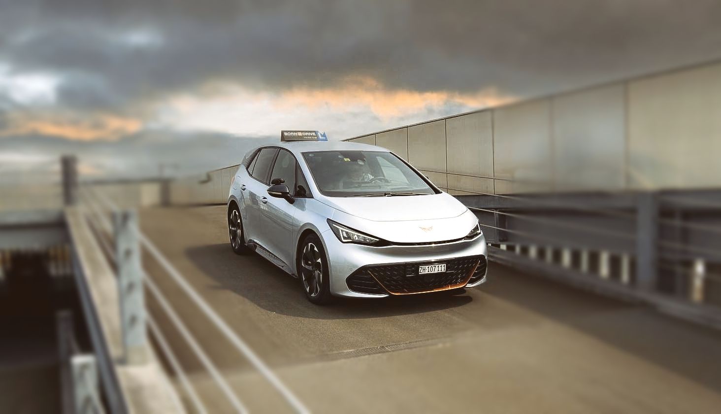 Ein silbriges Auto fährt auf einer Brücke.