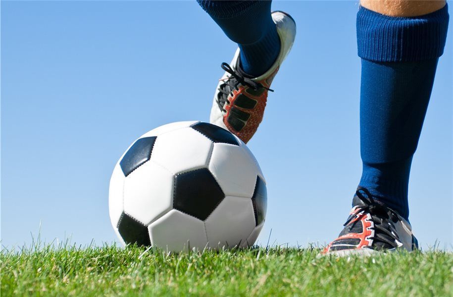 Ein Fußballspieler kickt einen Fußball auf einem Feld.