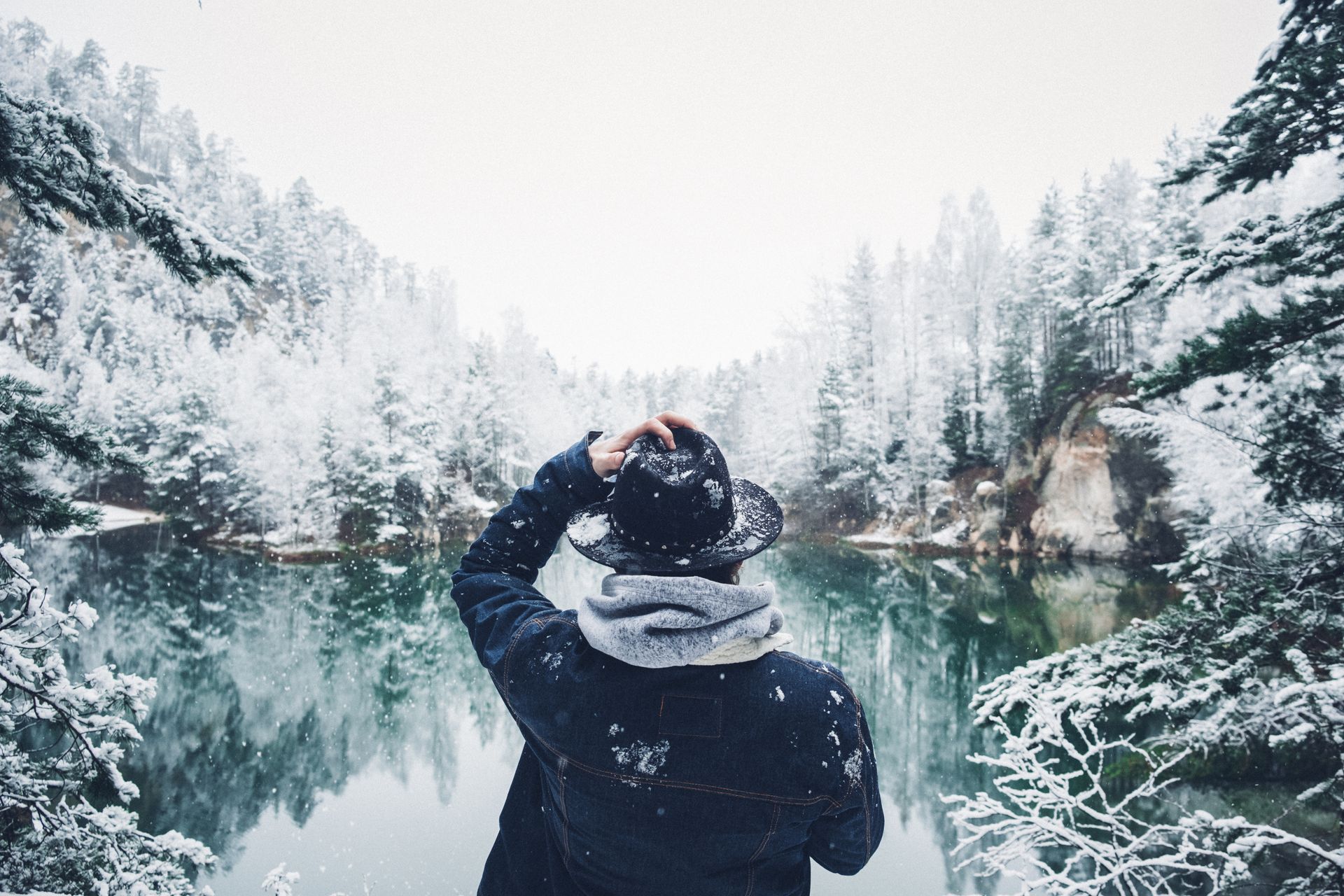 A person is holding a magnifying glass over a group of wooden houses.