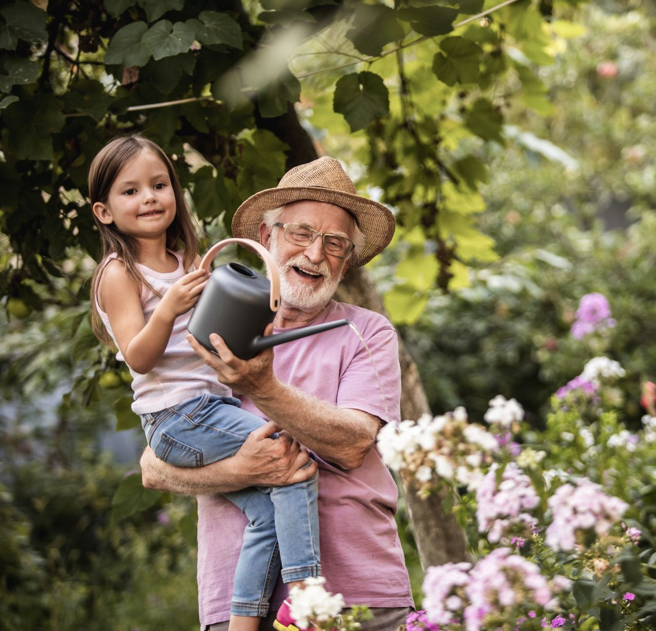 A woman and a child are laying under a blue blanket on a bed.