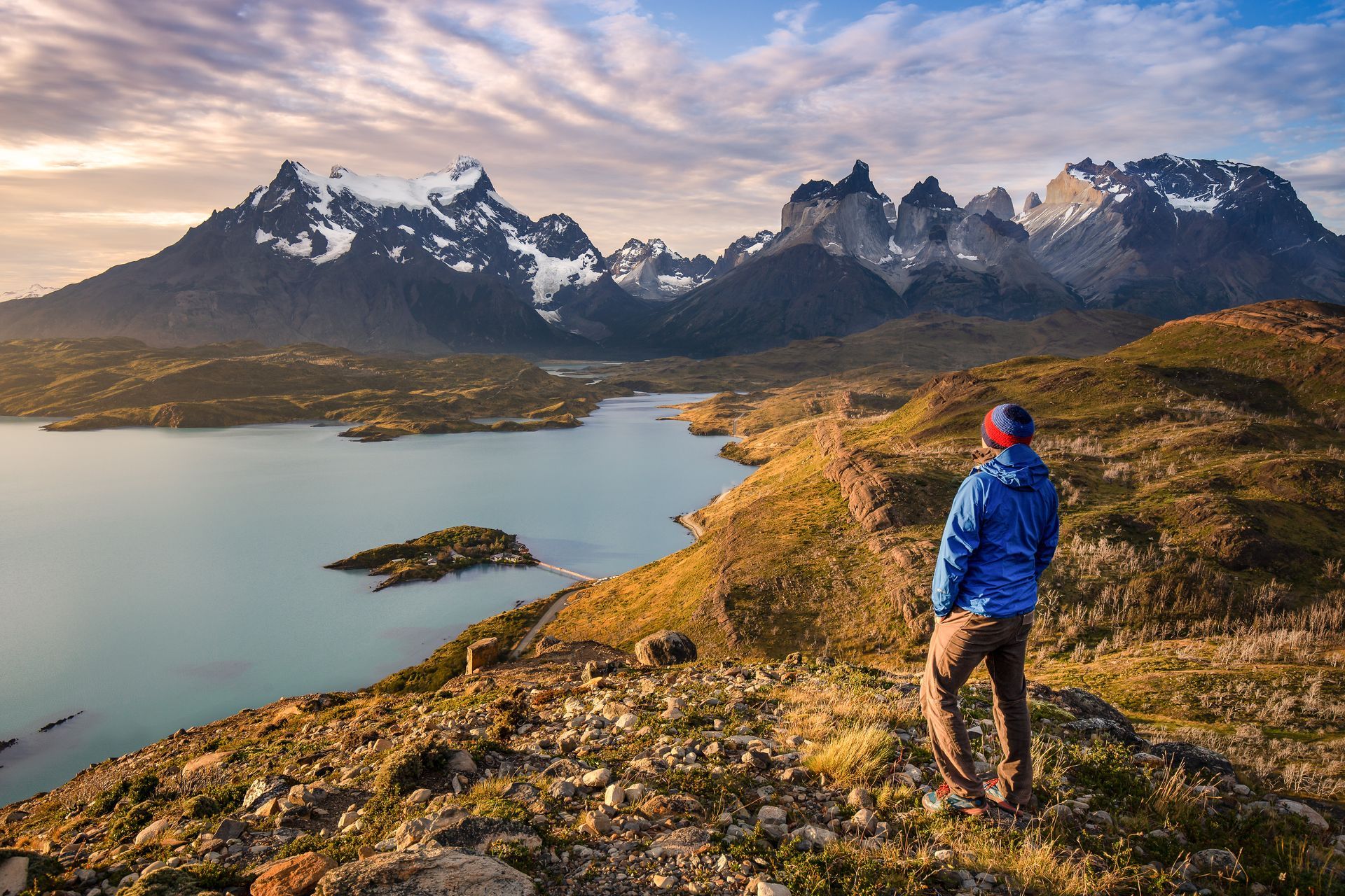 A woman with a backpack is standing in front of a mountain.