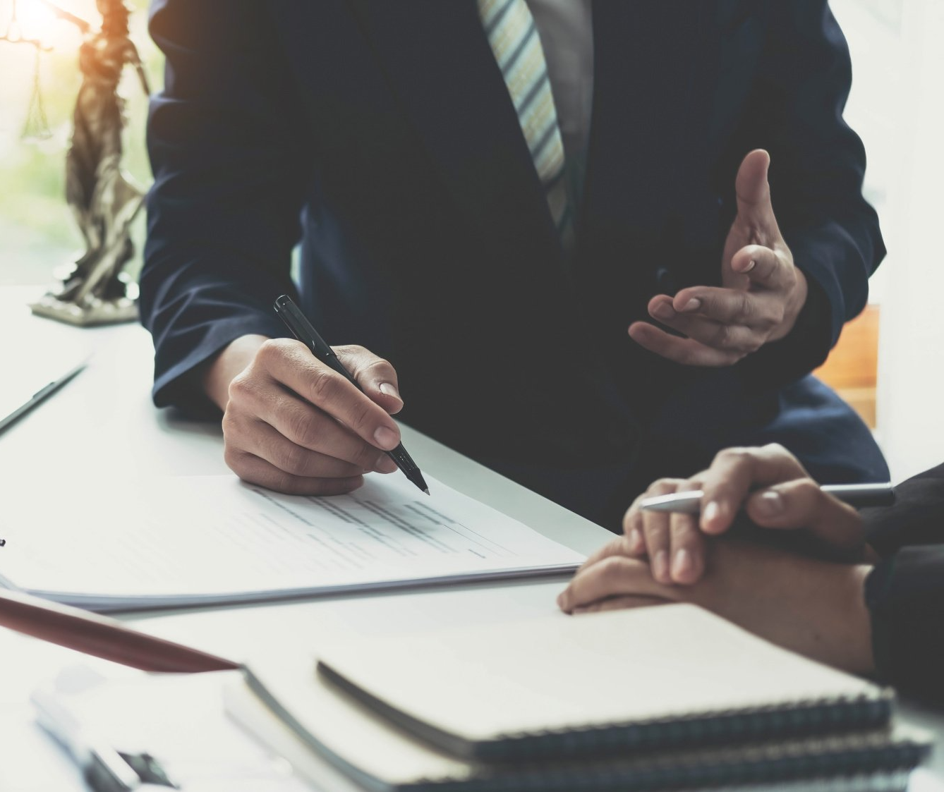 A man in a suit and tie is writing on a piece of paper