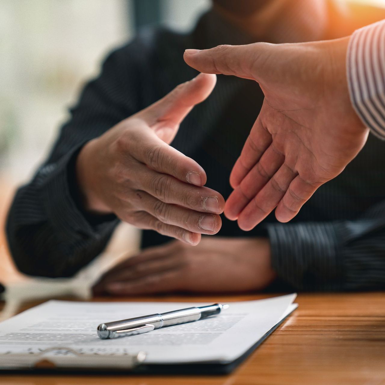 A man is shaking hands with another man while sitting at a table.
