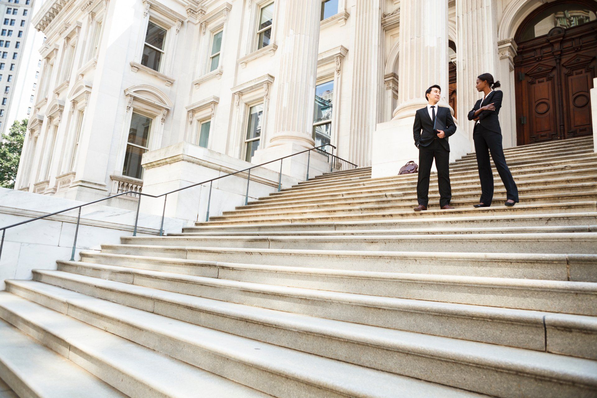 A man and a woman are standing on the steps of a building.