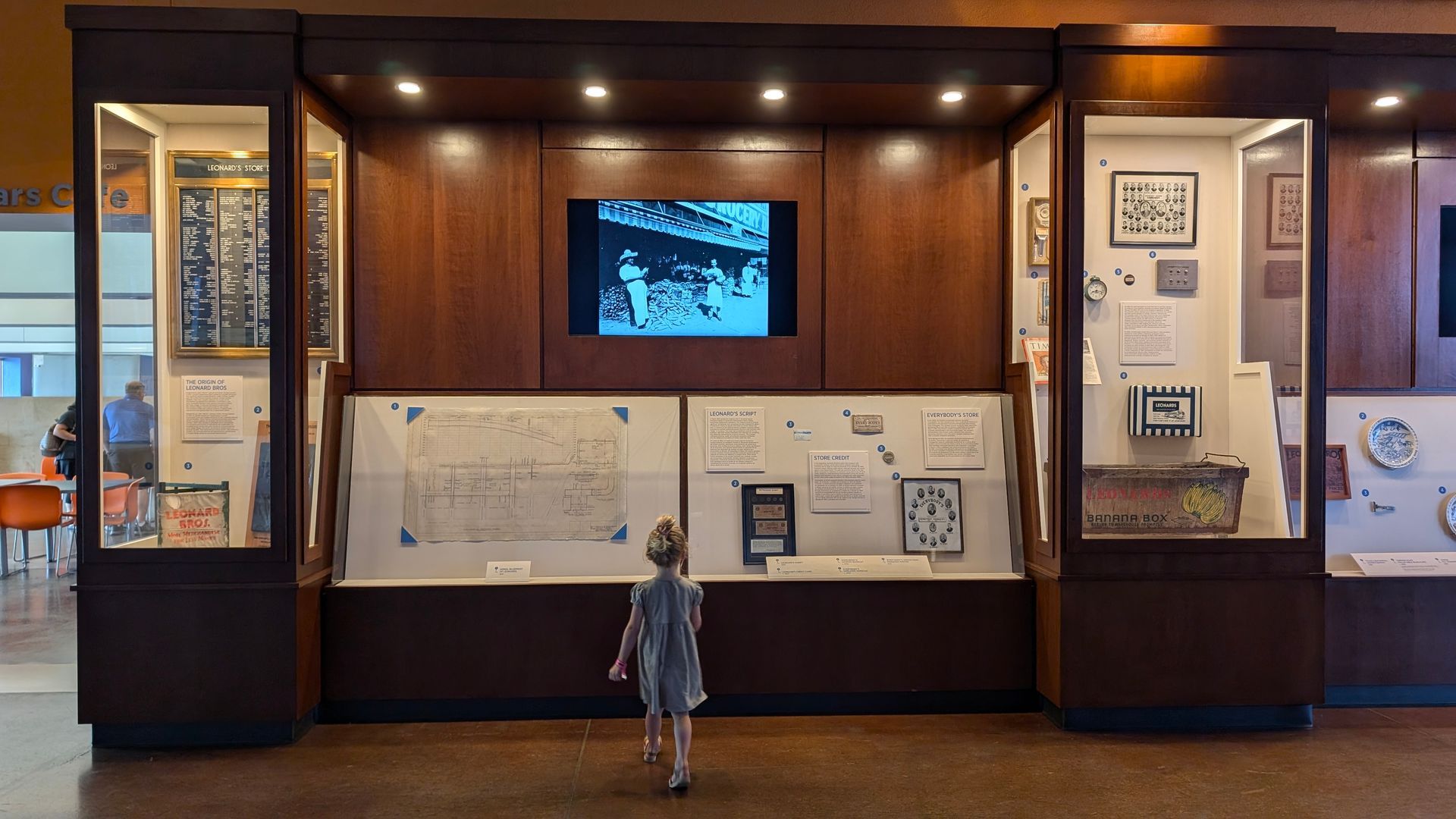 A little girl is standing in front of a display case in a museum.