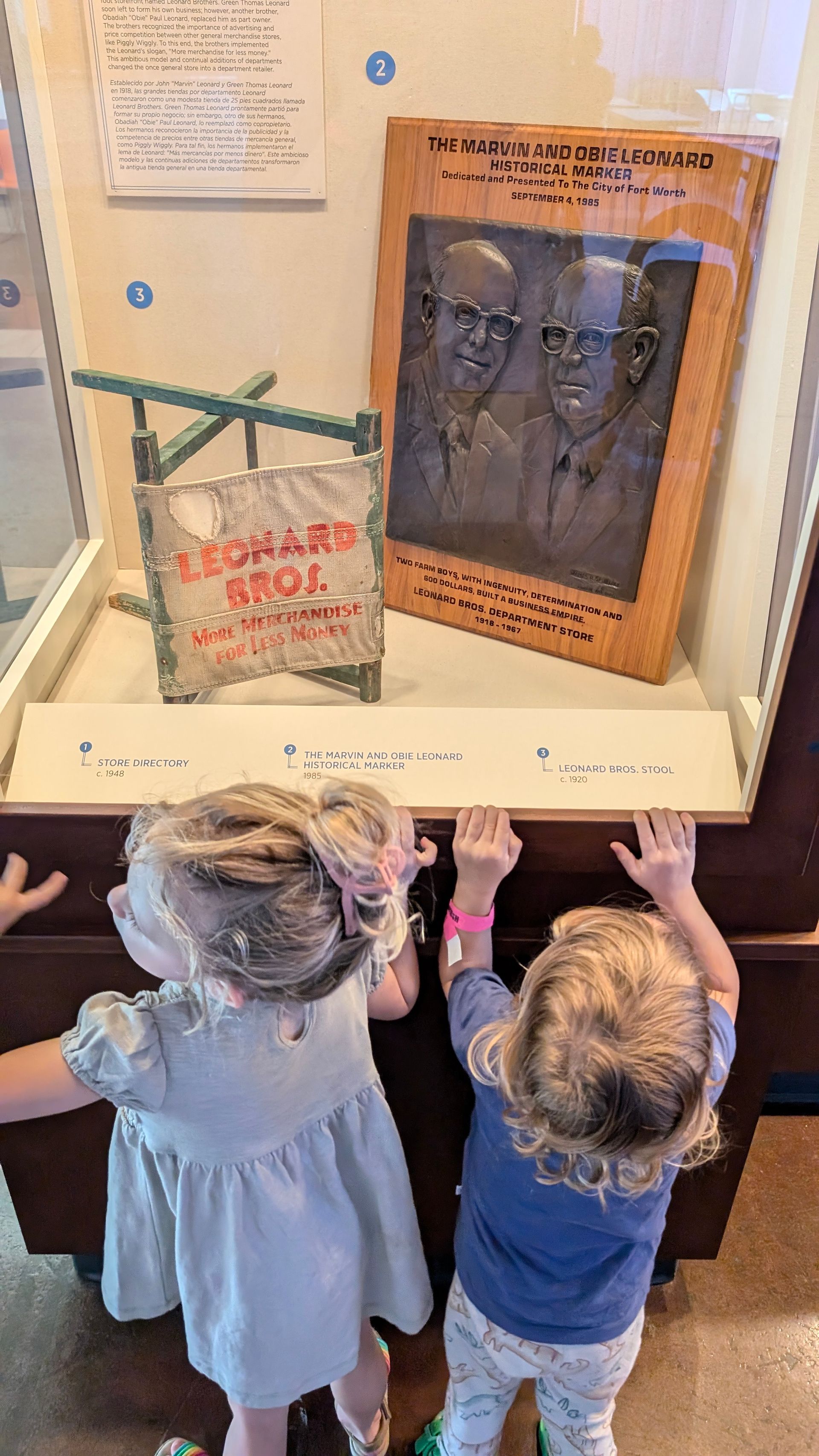 Two little girls are looking at a display case in a museum.