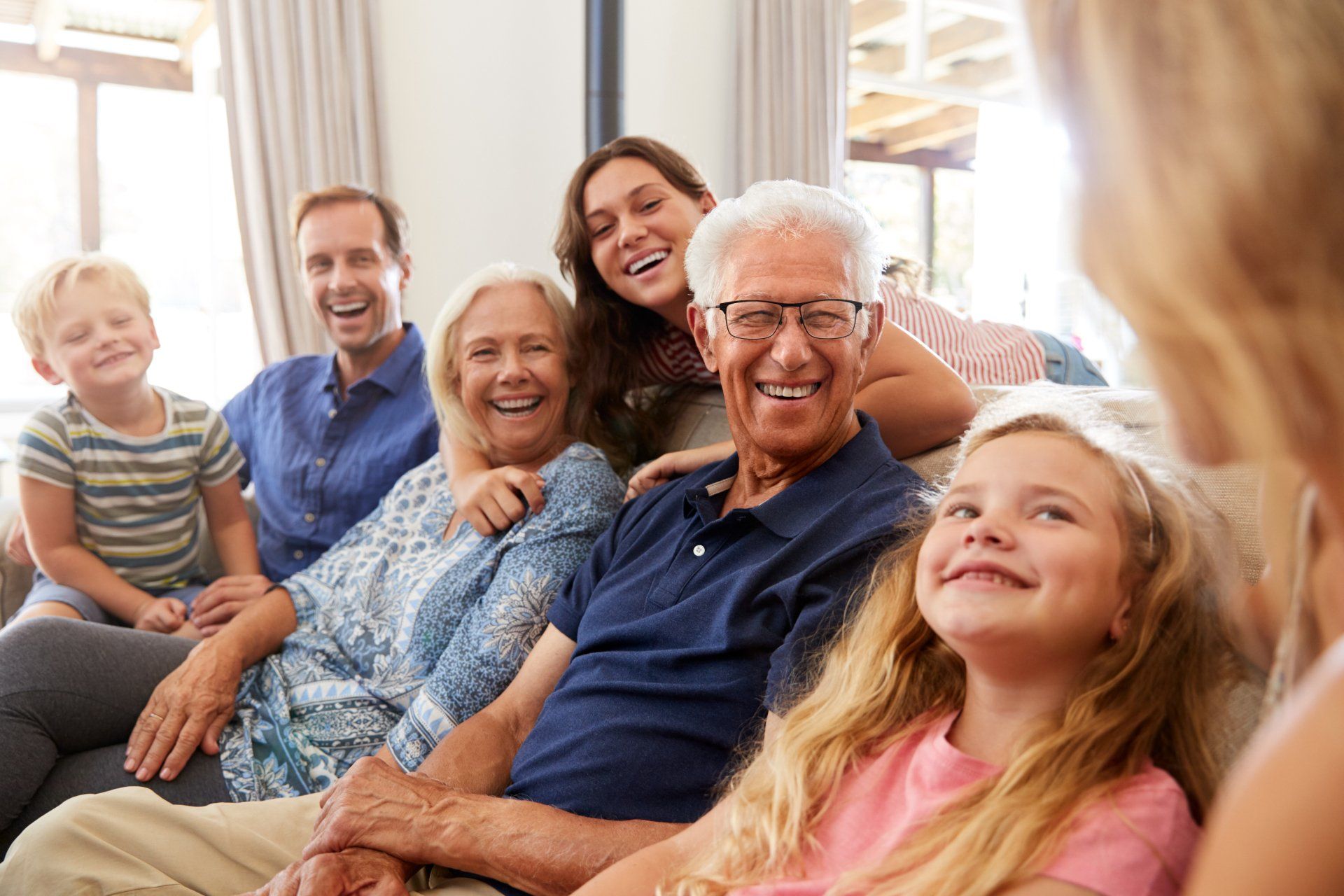 A large family is sitting on a couch in a living room.