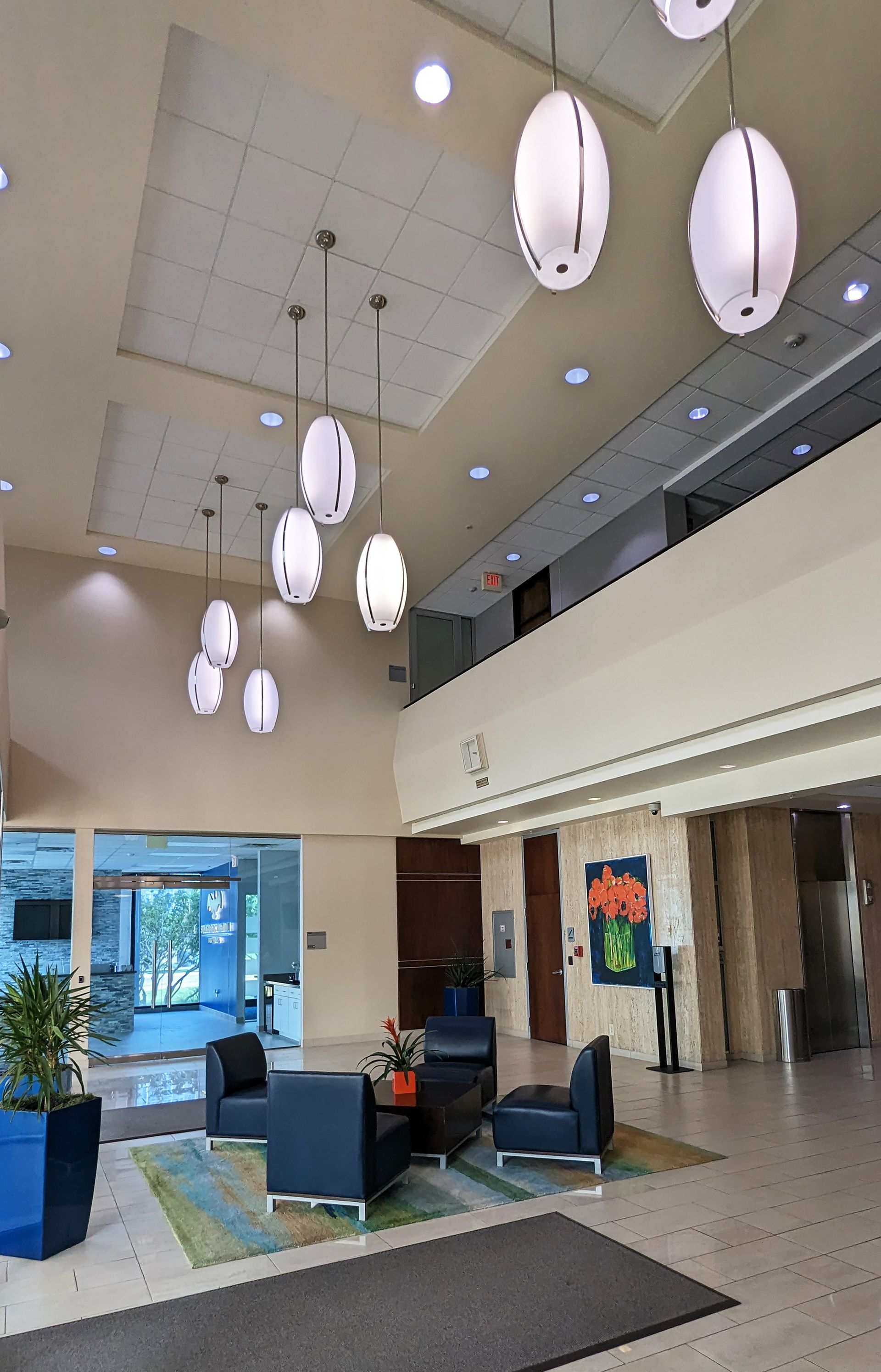 A large lobby with a lot of furniture and lamps hanging from the ceiling.
