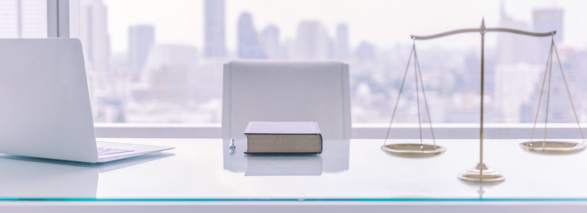 A desk with a laptop , book , scales of justice and a book on it.