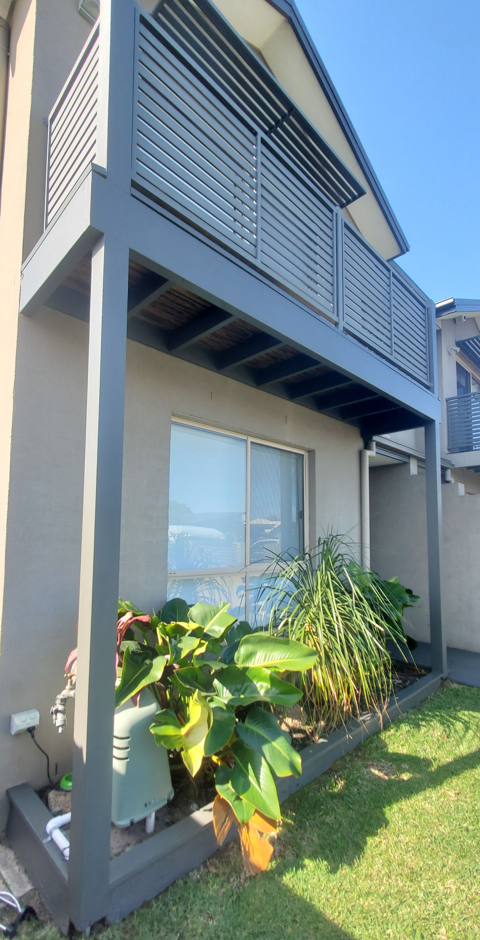 A house with a balcony and a lawn in front of it — JWP Painting & Property Services in Ettalong Beach, NSW