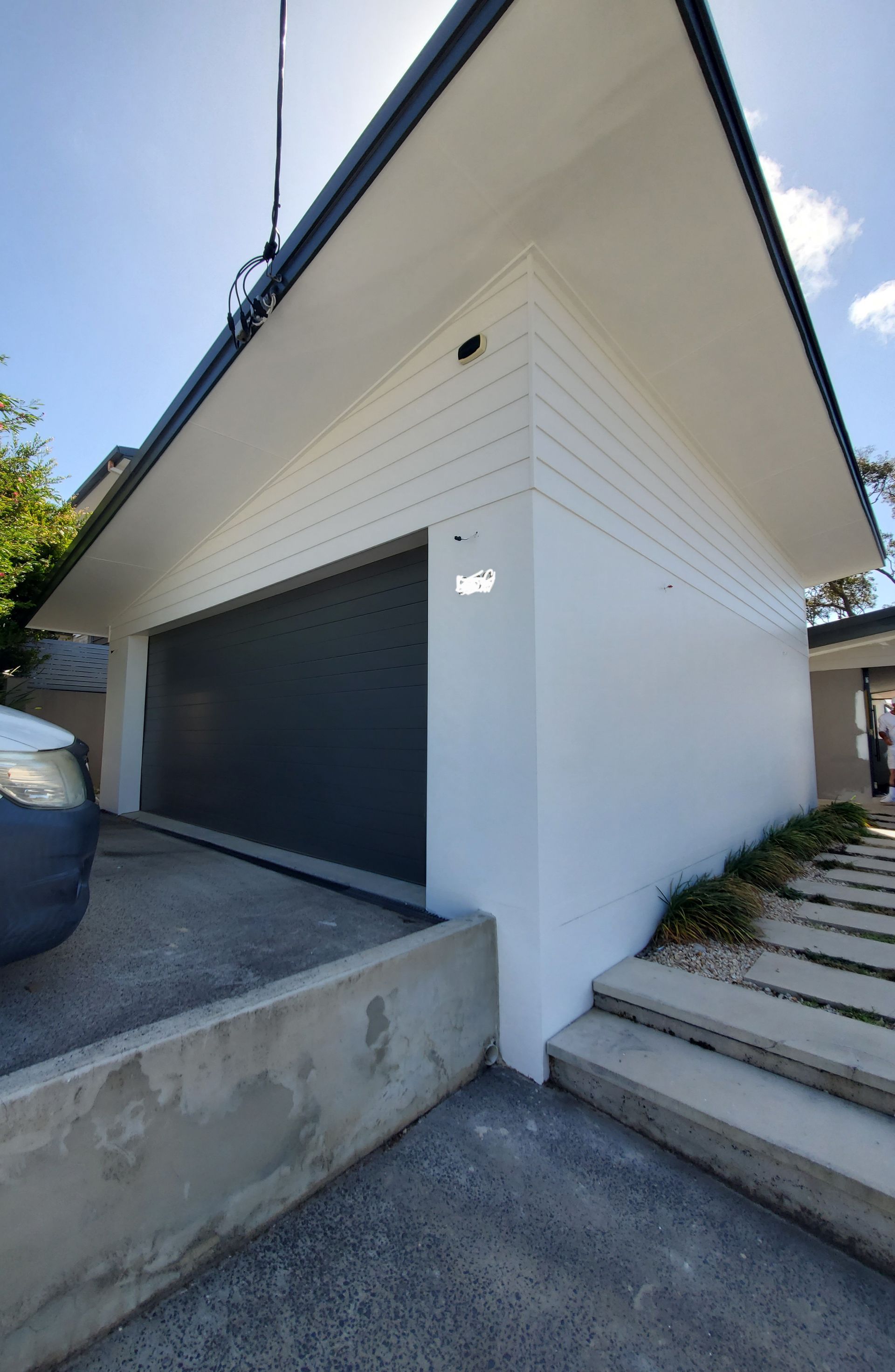 A car is parked in front of a white house with a black garage door — JWP Painting & Property Services in Ettalong Beach, NSW