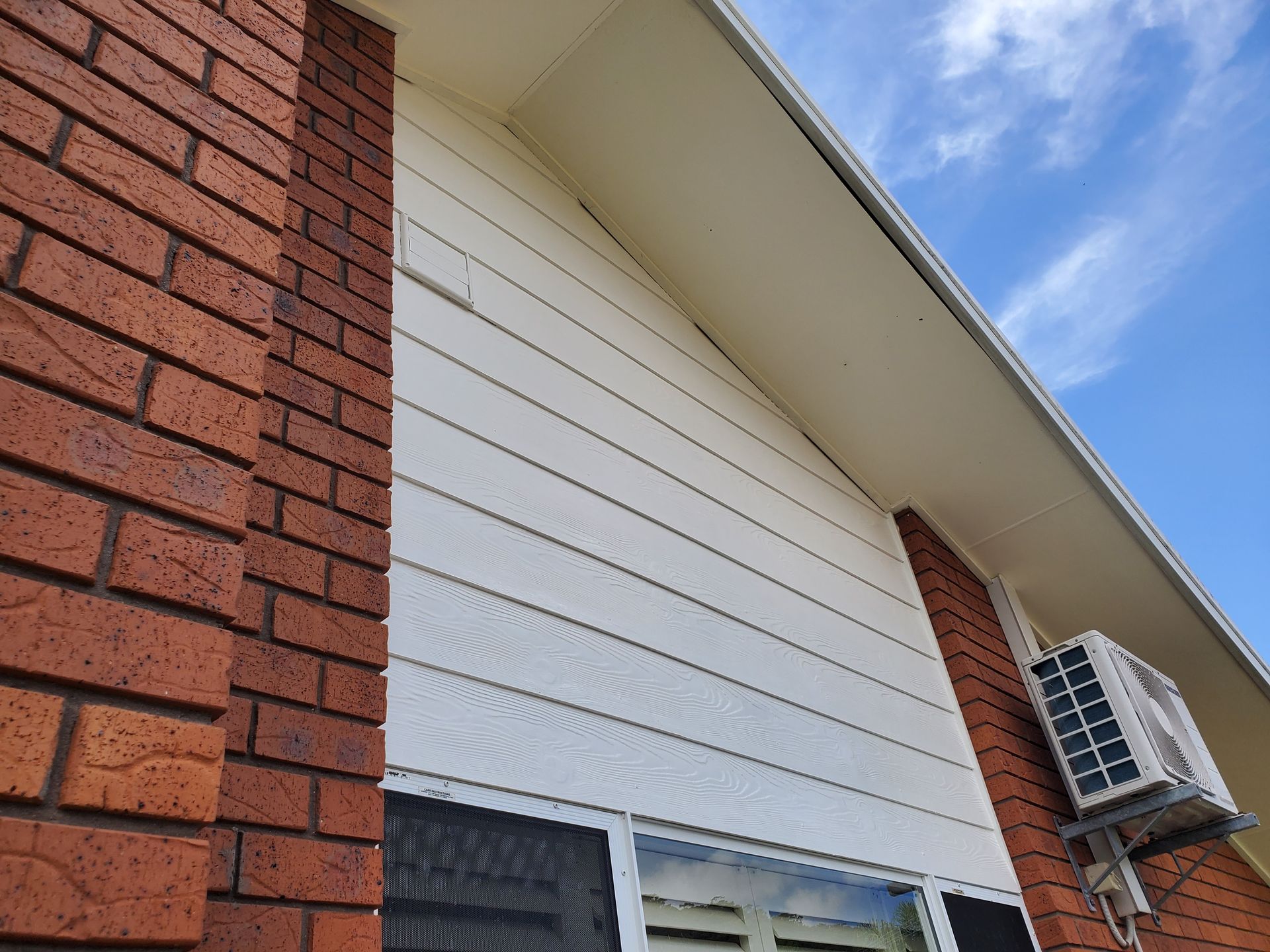 A brick building with a white siding and a window — JWP Painting & Property Services in Ettalong Beach, NSW