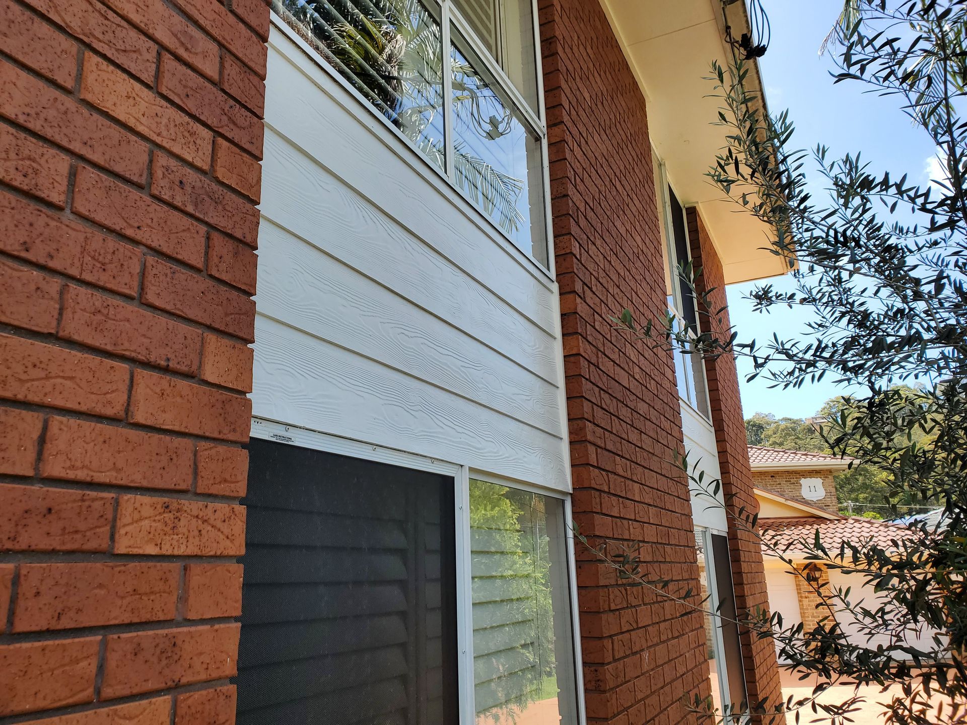 A brick building with a white siding and a window — JWP Painting & Property Services in Ettalong Beach, NSW