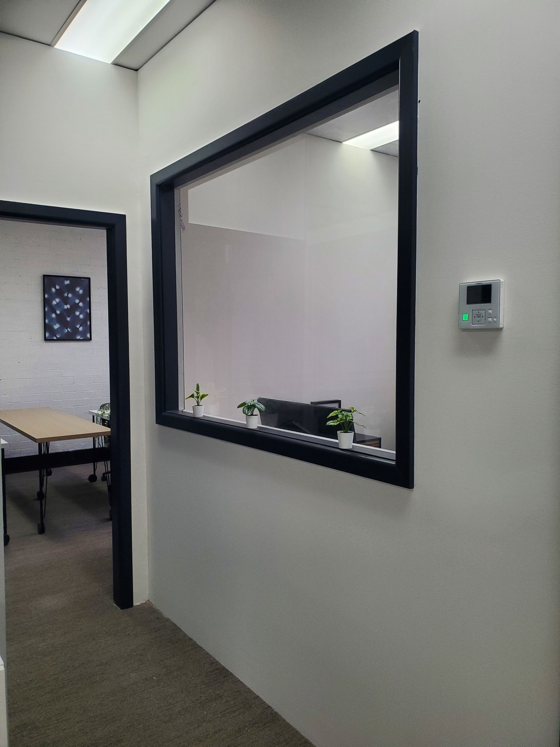 A hallway with a large window and a thermostat on the wall — JWP Painting & Property Services in Ettalong Beach, NSW