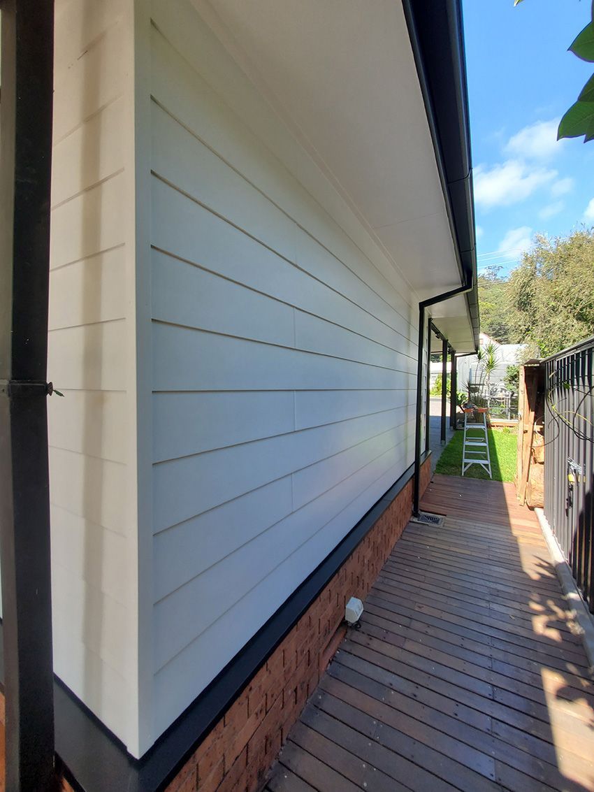 A White House with a Black Gutter on the Side of It — JWP Painting & Property Services in Ettalong Beach, NSW