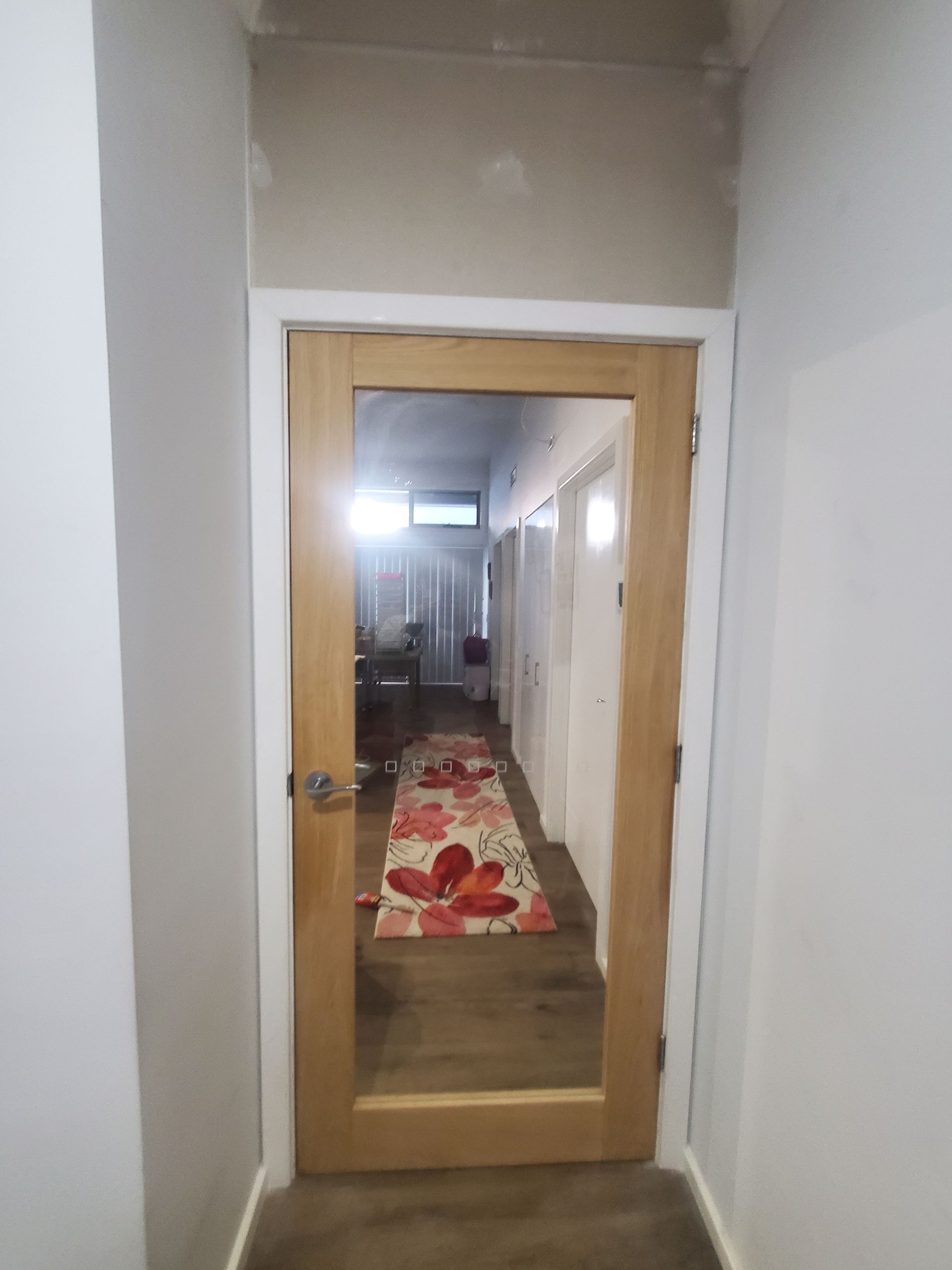A hallway with a mirrored door and a rug on the floor.