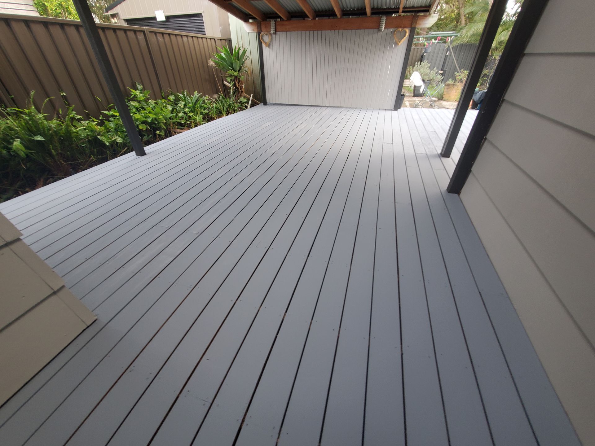 A gray deck with a fence in the background