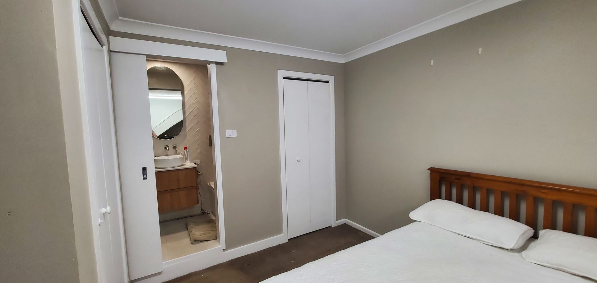 A bedroom with a bed and a bathroom with a sliding door — JWP Painting & Property Services in Ettalong Beach, NSW