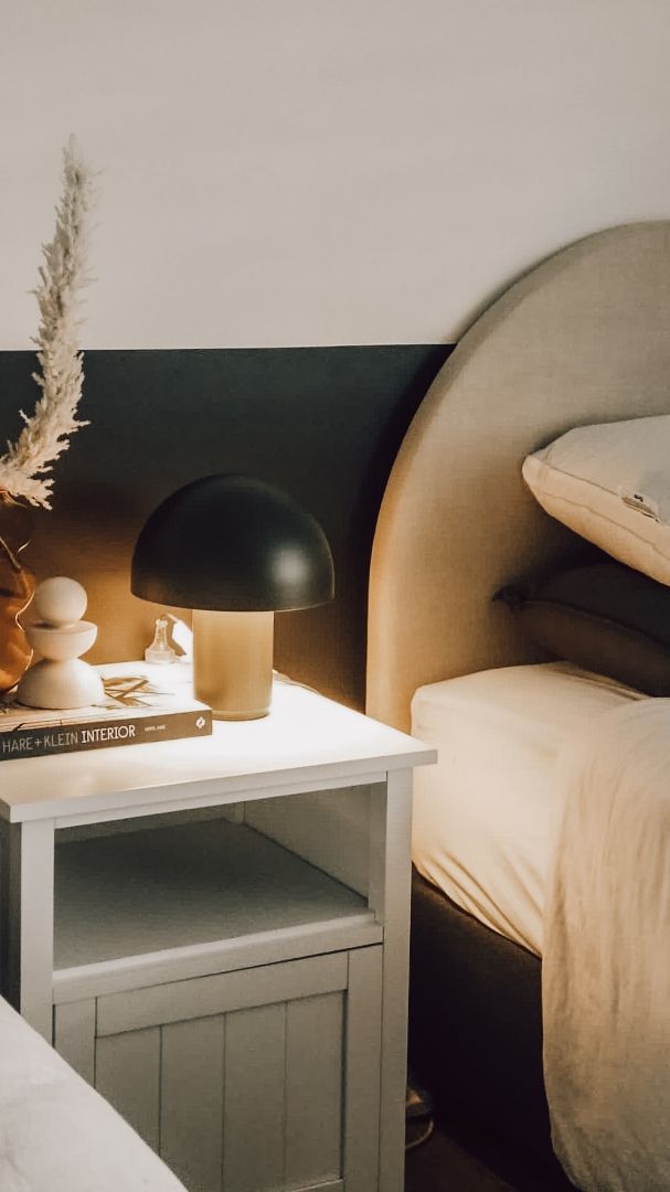 A nightstand with a lamp and a book on it next to a bed — JWP Painting & Property Services in Ettalong Beach, NSW