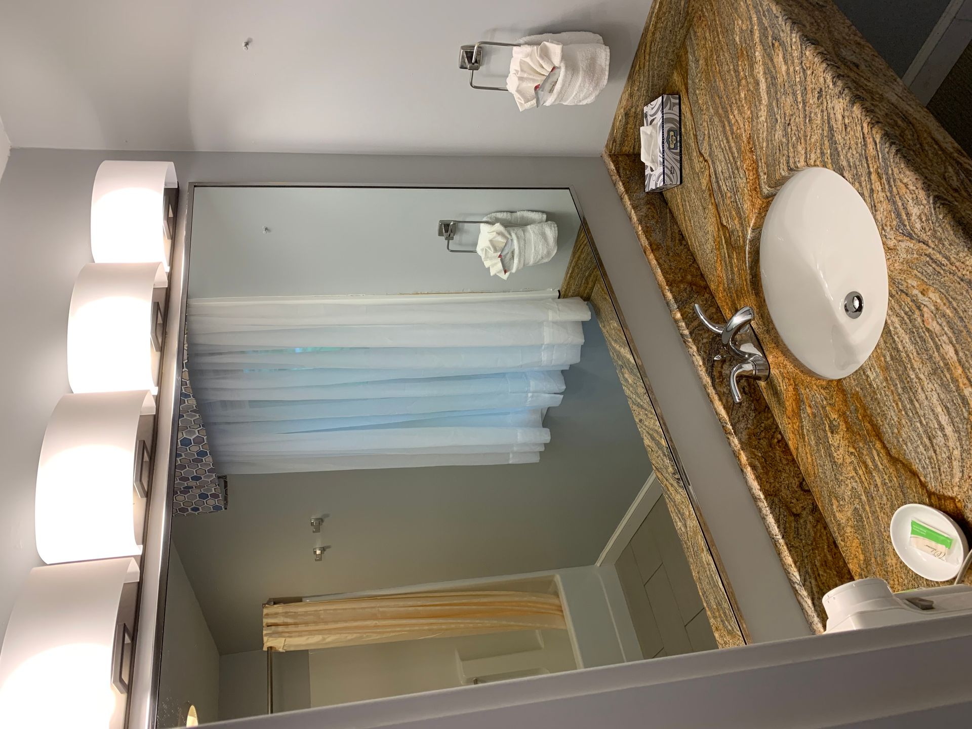 A bathroom with a sink , mirror and shower curtain.