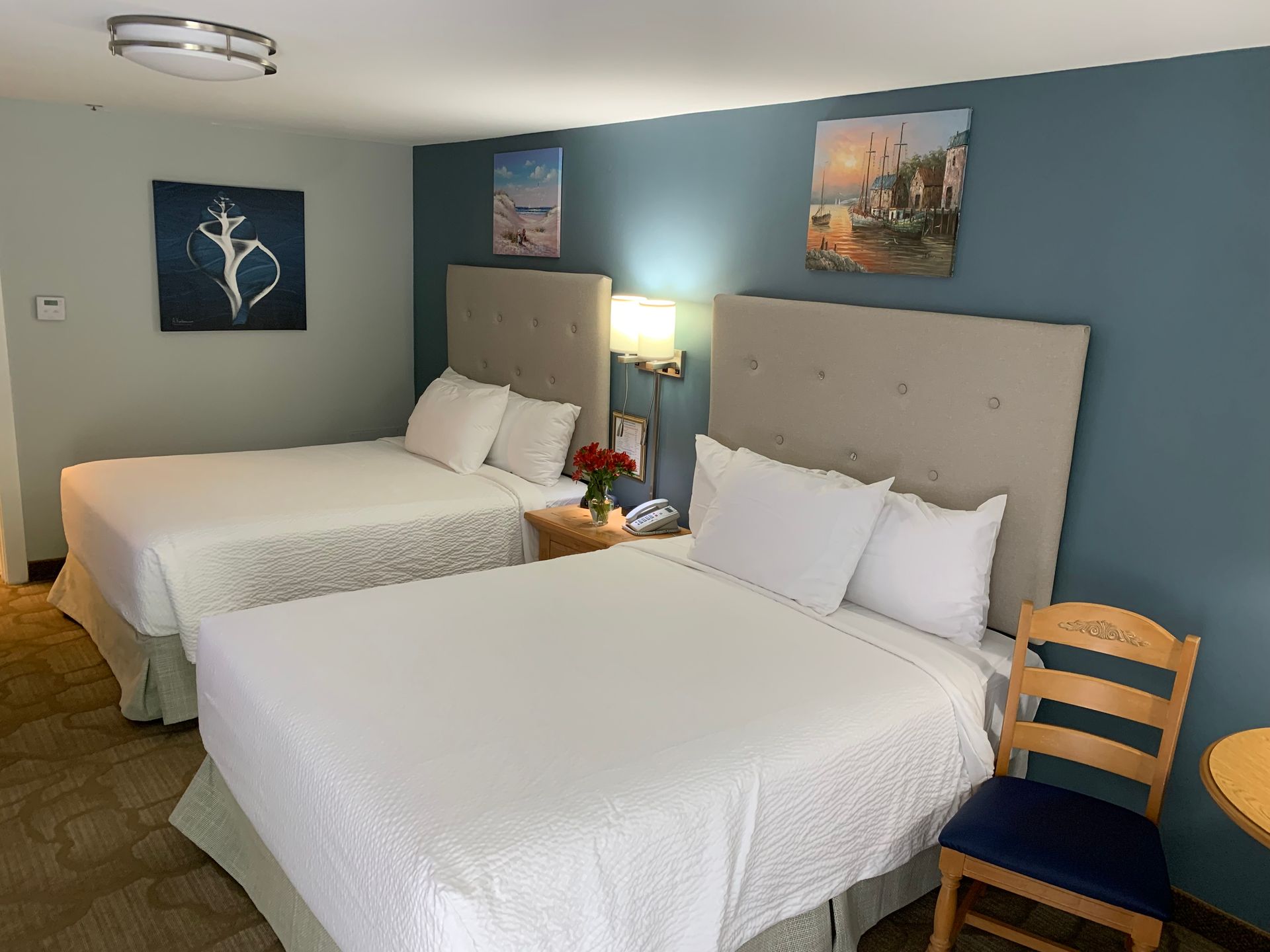 A hotel room with two beds , a chair and a table.