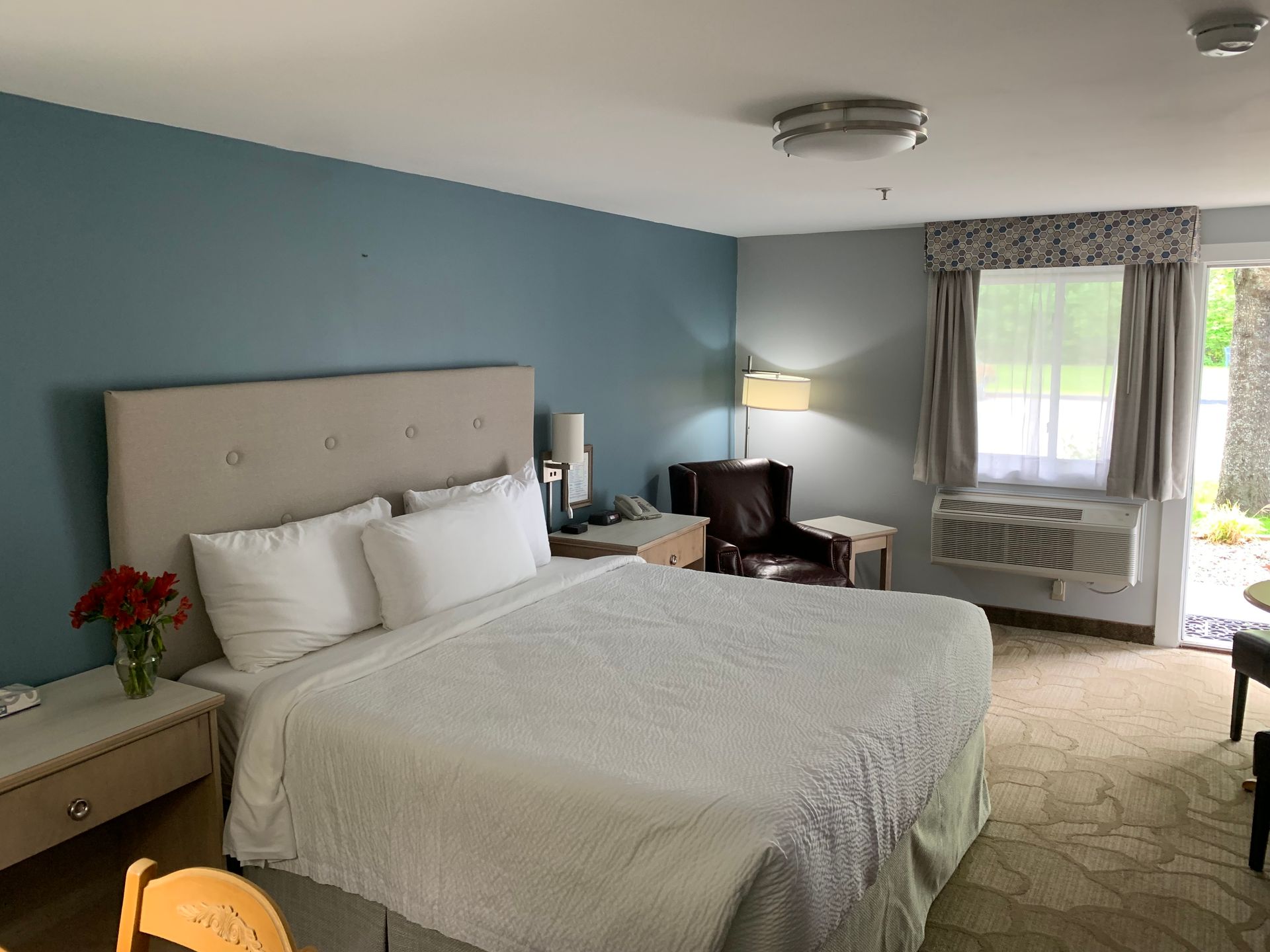 A hotel room with a king size bed and a chair.