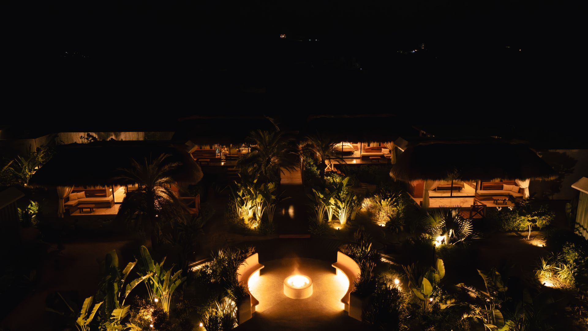 Una vista aérea de un hotel por la noche con una fogata en el medio.