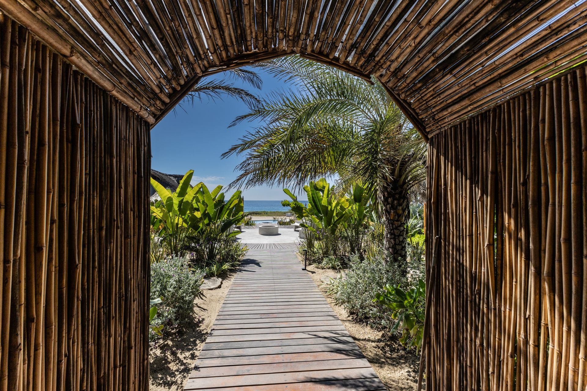 Un túnel de madera que conduce a una playa con palmeras.