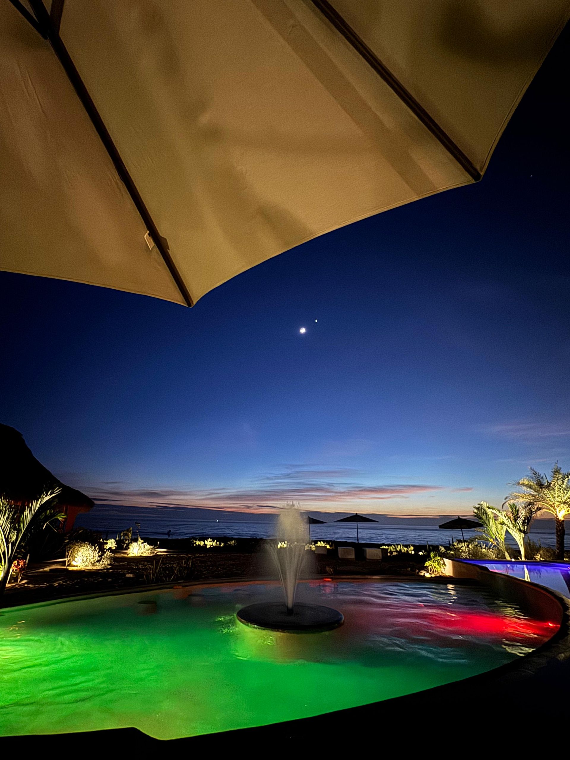 Una piscina con una fuente en el medio por la noche.