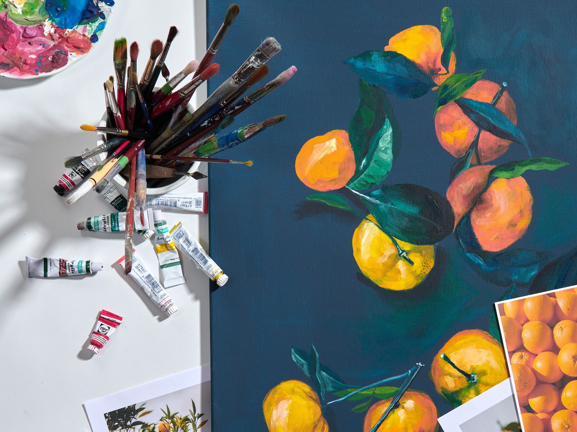 A painting of oranges and brushes on a table
