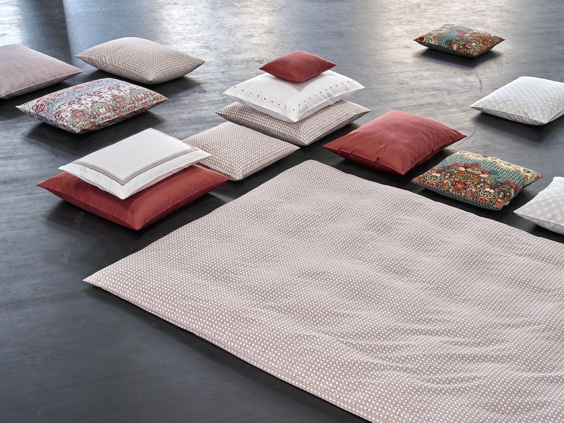 A rug and pillows are stacked on top of each other on the floor.